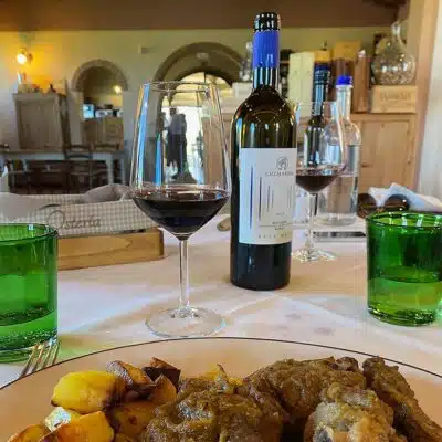 Das Bild zeigt eine Flasche Rotwein ‚Ruit Hora‘ auf dem Tisch mit Speisen