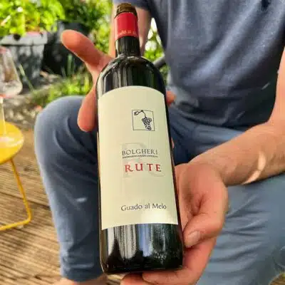 Das Bild zeigt eine Flasche Rotwein "Rute " in den Händen eines Mannes.